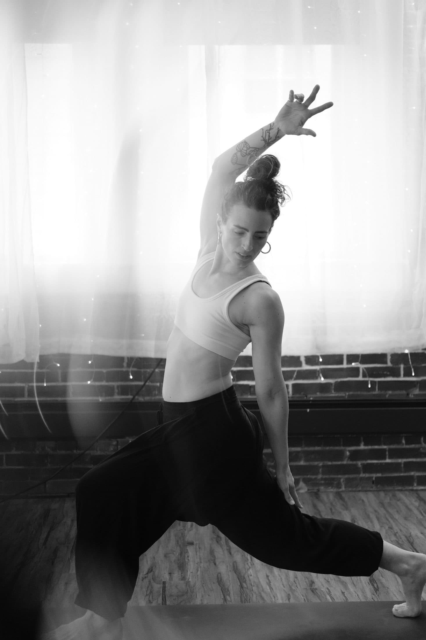 Black-and-white photograph of a low lunge with one arm curved overhead