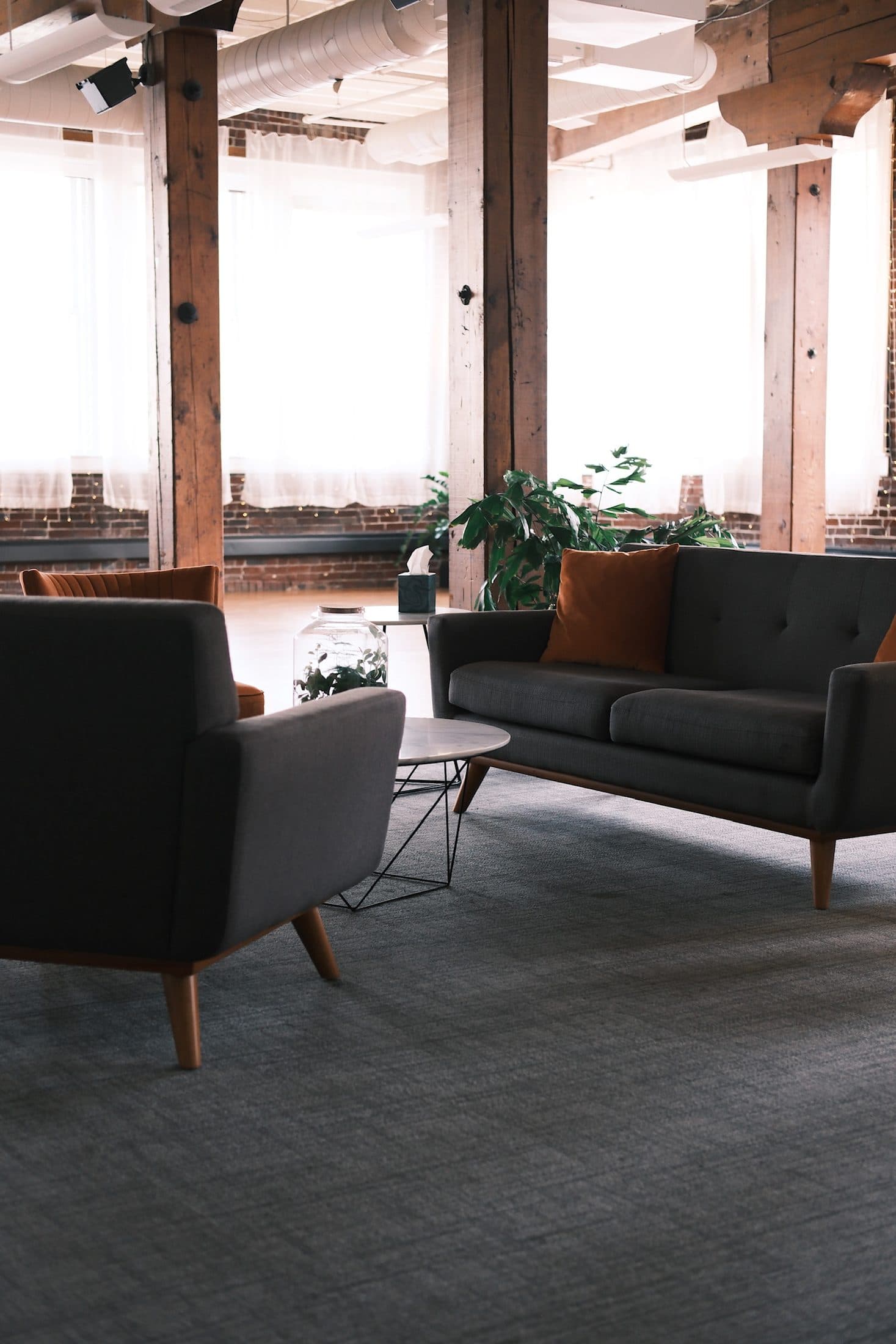 Lounge with a charcoal sofa and armchairs among timber columns and plants