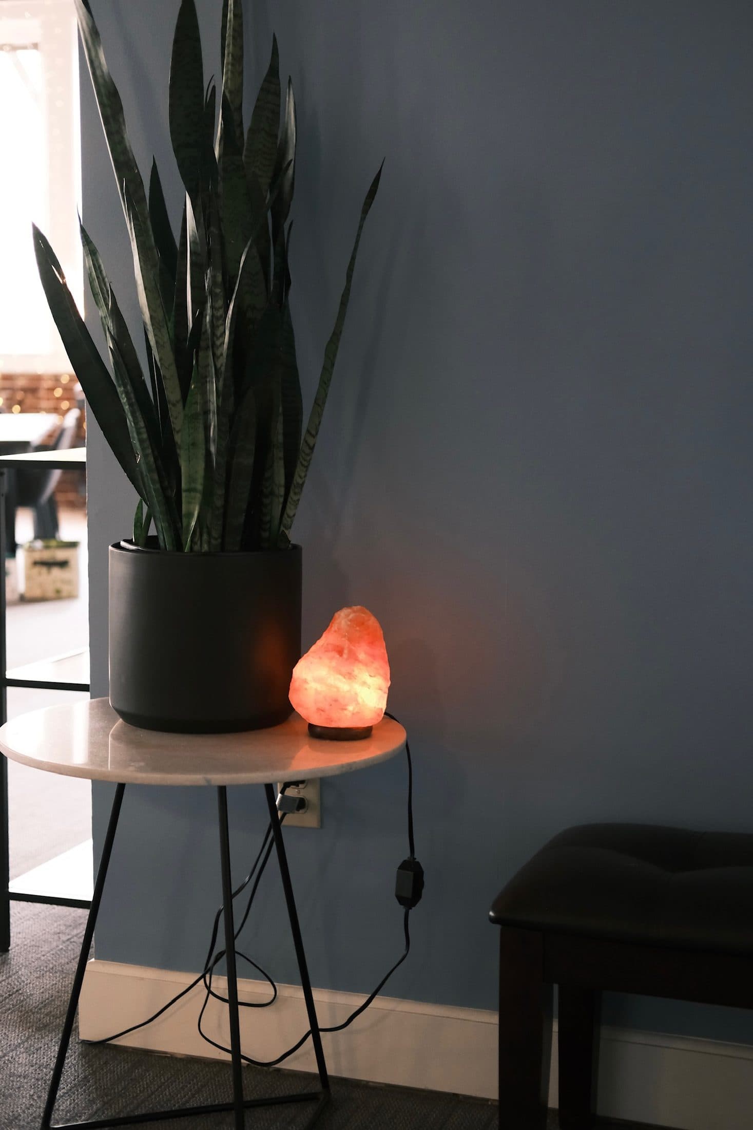 Snake plant and a salt lamp glowing on a small marble side table