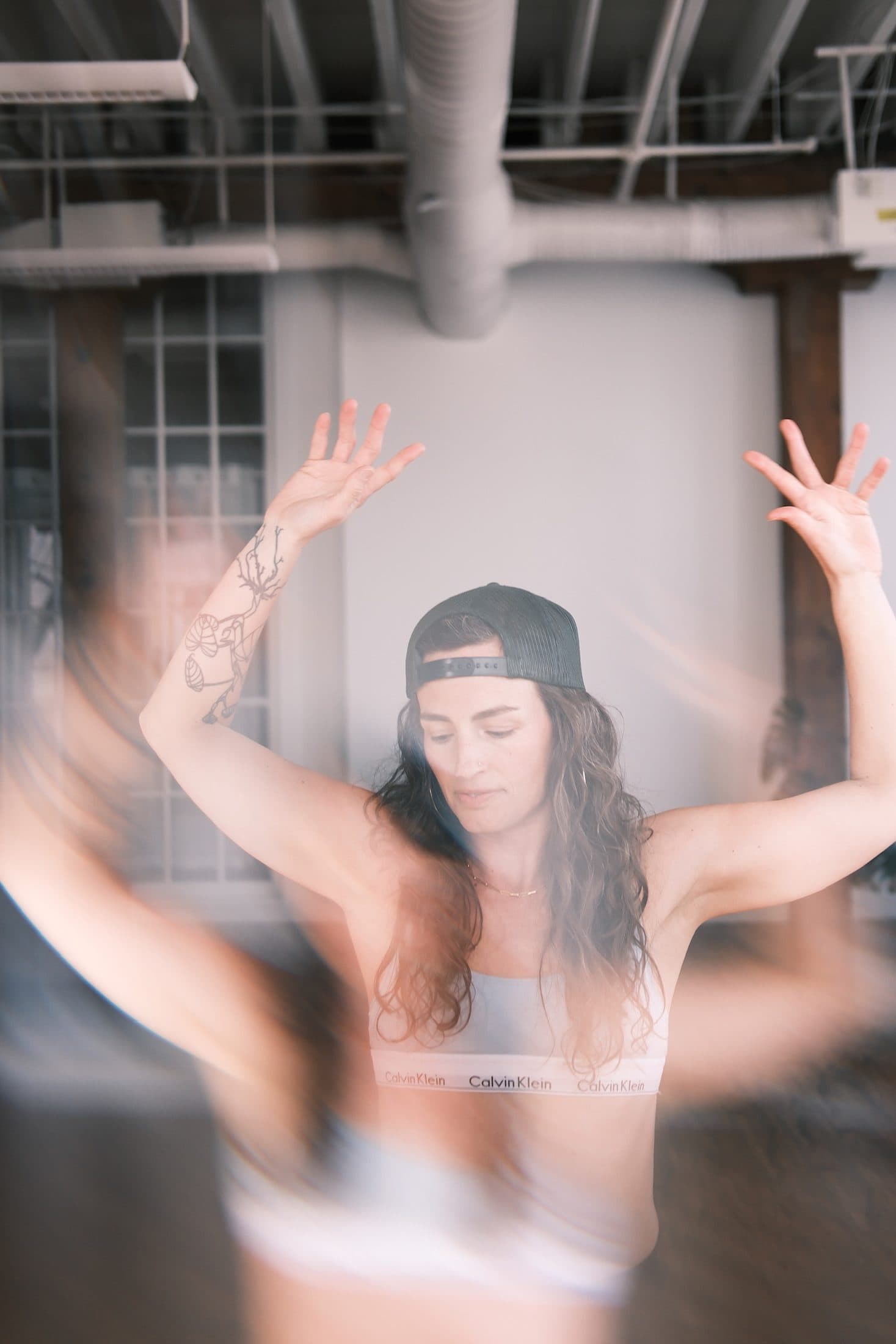 Double-exposure feel: practitioner with both arms lifted, echoed by her own motion