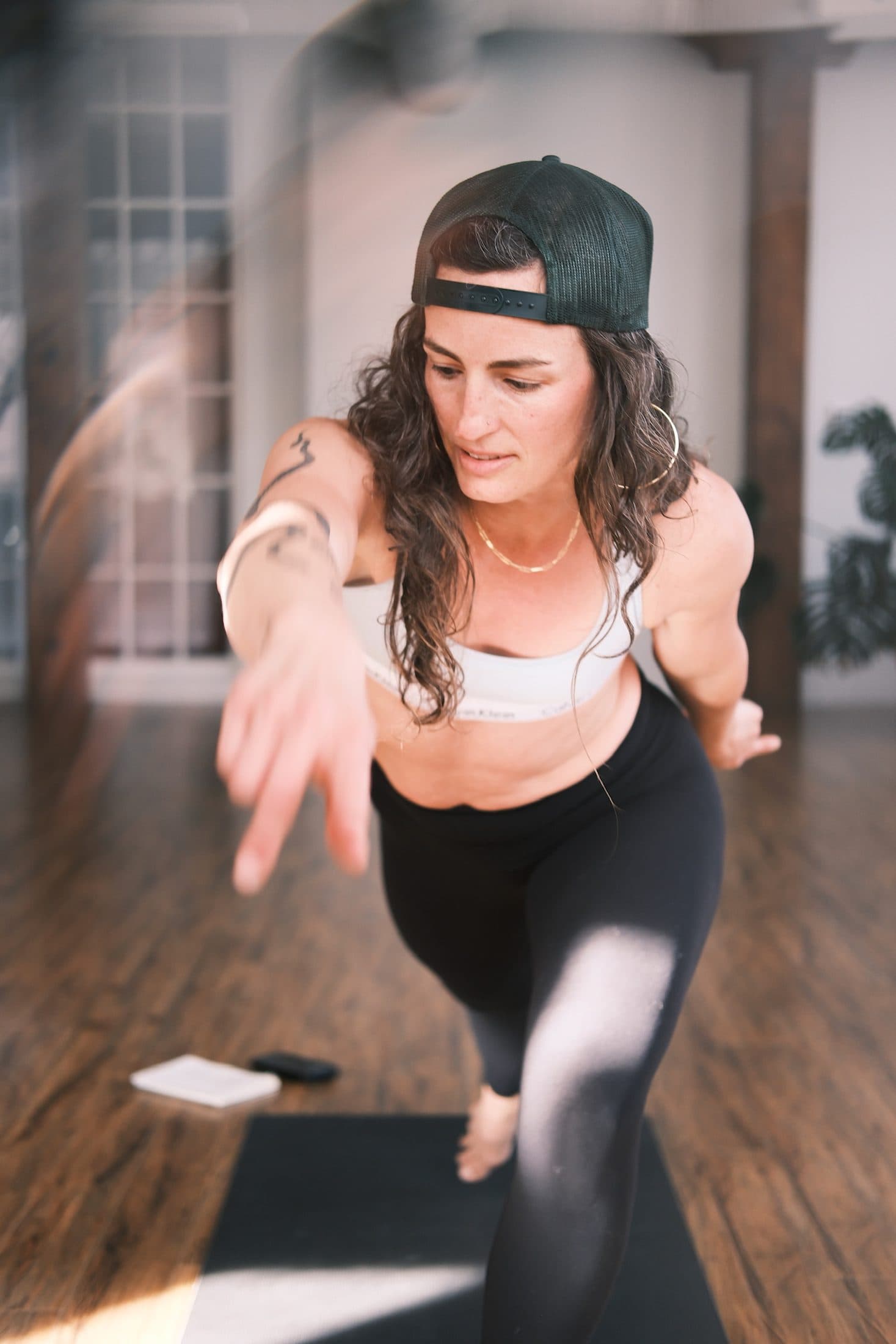 Practitioner stepping forward on the mat, reaching toward the camera in warm light